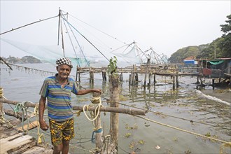 Indian fisherman standing at Chinese fishing nets, behind the Arabian Sea, Kochi, Kerala, India,