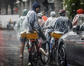 Tourists on a Berlin On Bike cycling tour protect themselves from heavy rainfall with rain capes,