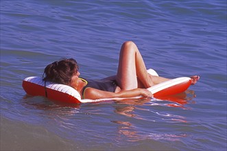 Woman lies on an air mattress in the water in Calella, Costa Brava, Barselona, ??Catalonia, Spain,