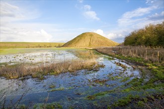 Silbury Hill ancient neolithic manmade chalk mound in Avebury, Wiltshire, England with flood water