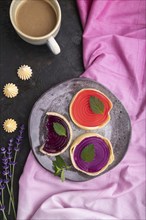 Sweet tartlets with jelly and milk cream with cup of coffee on a black concrete background and pink