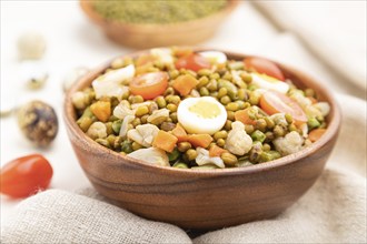 Mung bean porridge with quail eggs, tomatoes and microgreen sprouts on a white wooden background