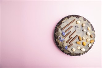 Homemade chocolate brownie cake with caramel cream and almonds on a pastel pink background. Top