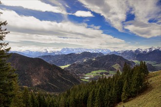 Panoramic view of the snow-covered Chiemgau mountains and green hills above the village of