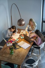 Homeschooling, during the lockdown in January 2021, mother helps her two daughters, at home,