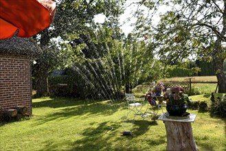 Europe, Germany, Lower Saxony, Stade district, garden in summer, garden table, water sprinkler,