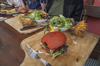 Burger with fries and salad served on a wooden board, Bavaria, Germany, Europe