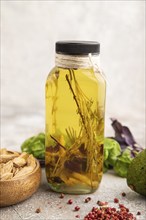 Sunflower oil in a glass jar with various herbs and spices, sesame, rosemary, avocado, basil,