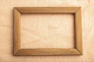 Wooden frame on smooth orange linen tissue. Top view, flat lay, natural textile background and