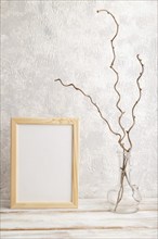 White wooden frame mockup with dried wine branch in glass on gray concrete background. Blank,