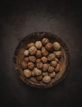 Fresh walnut in a shell, wooden plate, top view, no people