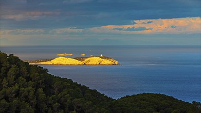 Sunrise in the bay of Sant Antoni, behind the island of Conillera in the first sunlight, Ibiza,