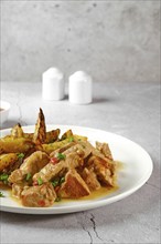 Closeup view of plate with beef goulash with baked in oven potato wedges