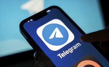 The social media Telegram messenger logo is being displayed on a smartphone screen and on a