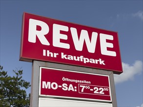 Signboard billboard with logo of retail chain retailer REWE ihr Kaufpark including long opening