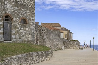 Tourists walking on promenade along ancient city wall in the town Pore?, Parenzo, seaside resort at