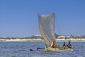 Malagasy fishermen sailing in traditional wooden fishing boat, outrigger canoe on the Indian Ocean,