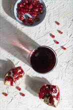 Glass of pomegranate juice on a white concrete background. Hard light, contrast. Top view, close