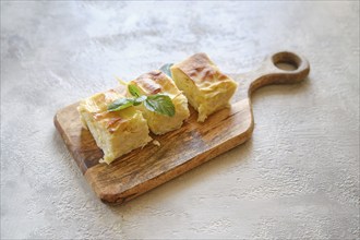 Overhead view of three pieces of Georgian cheese pie Achma on wooden cutting board