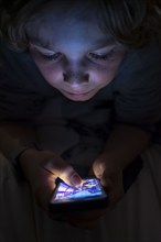 A boy plays computer games on a mobile phone, smartphone