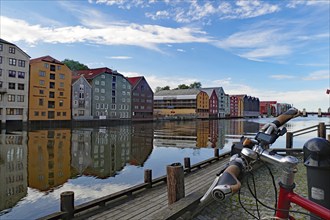 Wooden building on the riverbank with reflections in the water and a bicycle in the foreground,