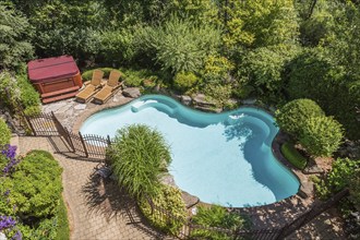 Top view of in-ground swimming pool surrounded by copper coloured wrought iron metal security fence