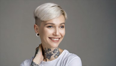 Portrait of a cheerful woman with a short haircut and visible tattoos in front of a grey