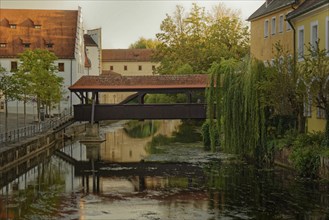 The old ship bridge leads over the calm river Vils with reflection in the water, Amberg, Upper