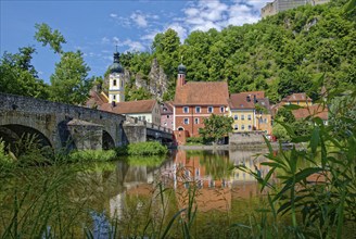 Ancient stone bridge over the river Naab with the church tower of St Michael and the leaning tower