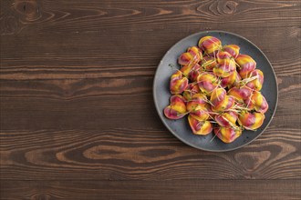 Rainbow colored dumplings with pepper, herbs, microgreen on brown wooden background. Top view, flat