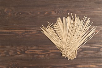 Japanese buckwheat soba noodles on brown wooden background. Top view, flat lay, copy space