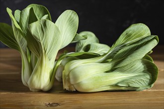 Fresh green bok choy or pac choi chinese cabbage on a gray wooden background. Hard light, contrast,