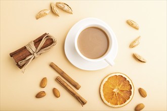 Composition with almonds, cinnamon and cup of coffee on orange pastel background. Blank, flat lay,