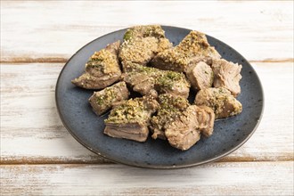 Stewed turkey fillet with garlic on white wooden background. Side view, close up