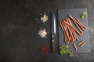 Traditional polish smoked pork sausage kabanos on a slate cutting board with salt and pepper on