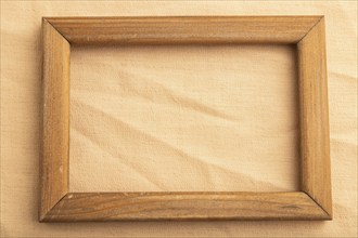 Wooden frame on smooth orange linen tissue. Top view, flat lay, natural textile background and