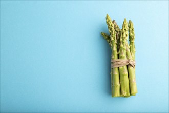 Bunch of fresh green asparagus on blue pastel background. Top view, flat lay, copy space. harvest,