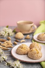 Almond cookies and a cup of coffee on a gray and pink background and green linen textile. Side