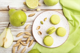 Green macarons or macaroons cakes with cup of coffee on a white wooden background and green linen