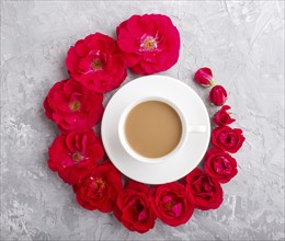 Red rose flowers in a spiral and a cup of coffee on a gray concrete background. Morninig, spring,