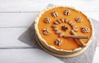 Traditional american sweet pumpkin pie decorated with nuts, on white wooden background. close up