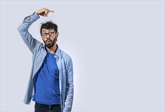 Surprised handsome man pointing to the side isolated. Latin man pointing a banner to the side