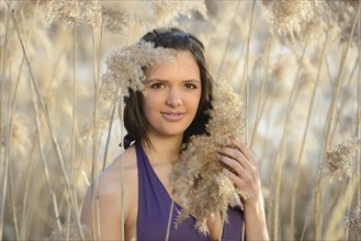 Close-up of a woman in a purple bikini holding dry reeds, Bavaria