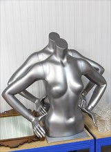 Two silver metallic faceless female mannequin torsos in auction room, UK