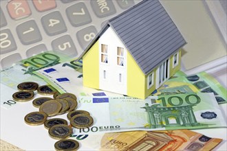 Concept photo with model house, euro notes and coins