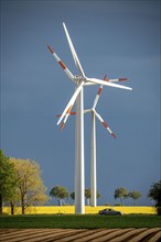 Wind turbines on a rape field, dark rain clouds, in the Rhenish lignite mining area, near