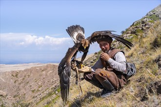 Traditional Kyrgyz eagle hunter with eagle in the mountains, near Kysyl-Suu, Kyrgyzstan, Asia