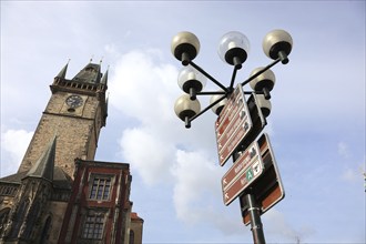 Gothic tower of the Old Town Hall on the Old Town Square and a street lamp with signs to the sights