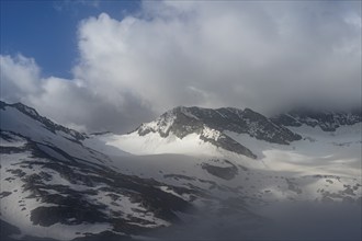 Cloudy, atmospheric mountain landscape with glaciated mountain peaks, Dosso Largo summit with