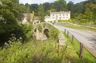 Bridge crossing the River Frome and the classical Georgian facade of Iford Manor, near Freshford,